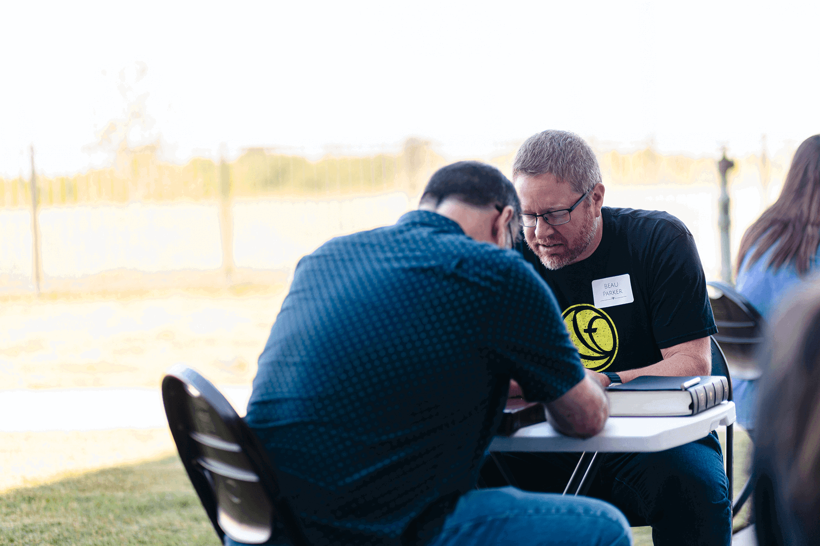Men praying together at a table at HFBC